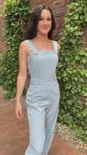 Load and play video in Gallery viewer, Arrive the most adorable jumpsuit ever when you walk in wearing this beautiful blue jumpsuit. This classy jumpsuit features scallop edges on the straps and along the top of the bodice. It has tabs with buttons for added style on the shoulders and waistline. Zip up back closure. Long tapered legs.    61% polyester, 37% cotton, and 2% spandex  Available in sizes x-small, small, medium, and large Zip back closure
