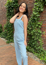 Load image into Gallery viewer, Arrive the most adorable jumpsuit ever when you walk in wearing this beautiful blue jumpsuit. This classy jumpsuit features scallop edges on the straps and along the top of the bodice. It has tabs with buttons for added style on the shoulders and waistline. Zip up back closure. Long tapered legs.    61% polyester, 37% cotton, and 2% spandex  Available in sizes x-small, small, medium, and large Zip back closure
